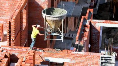 Bir işçi inşaat alanındaki tuğla bir duvara kapı çakıştırıyor.