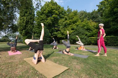 Yoga ustası kadın, dışarıda yoga yapmak için esneme egzersizleri yapıyor.