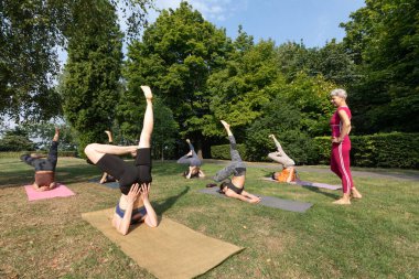 Yoga ustası kadın parkta yoga yapmak için yoga grupları kuruyor.