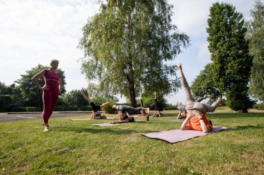 Yoga ustası kadın parkta yoga yapmak için yoga grupları kuruyor.