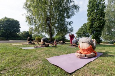 Kadın yoga ustası esneme egzersizlerine yardım ediyor.
