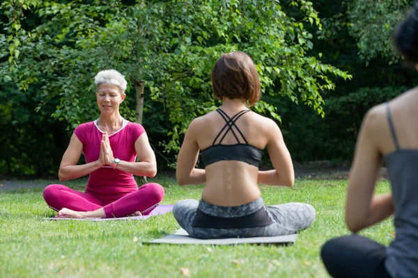 Maestro Yoga Femenino Sienta Una Alfombra Deportiva Enseña Grupo Mujeres —  Fotos de Stock