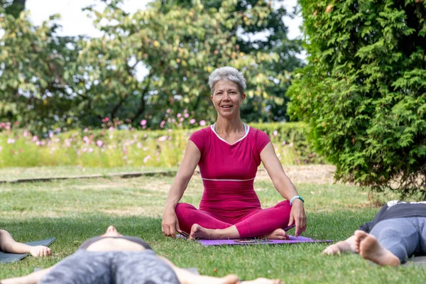 Yoga ustası Hatha seremonisi düzenliyor. Bir grup insan parkta yerde yatıyor.