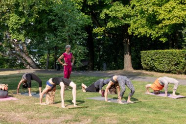 Yoga pozu. Dişi usta, köprü pozisyonunun uygulanmasını gözlemliyor.