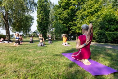 Yoga pozu. Kadın yoga ustası spor paspasına oturur ve ellerini arkadan kilitte tutar.