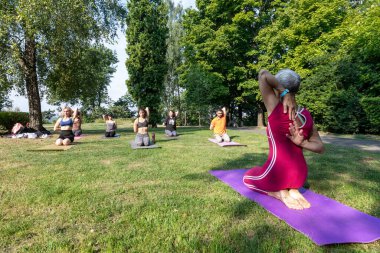 Yoga pozu. Kadın yoga ustası bir spor paspasına oturur ve ellerini arkadan kilide sabitler.