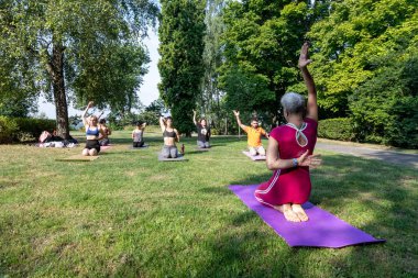 Yoga pozu. Kadın yoga ustası spor paspasına oturur ve elini kaldırır.