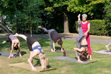 Yoga pozu. Kadın yoga ustası, grubun esneme egzersizleri yapmasına yardım ediyor.