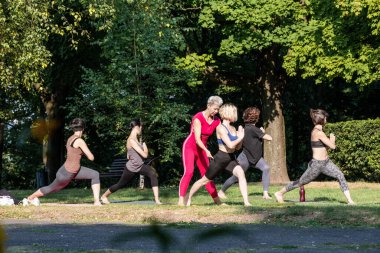 Kadın yoga ustası yoga eğitimini dışarıda yapıyor. Spor egzersizlerinin performansını gözlemliyor.