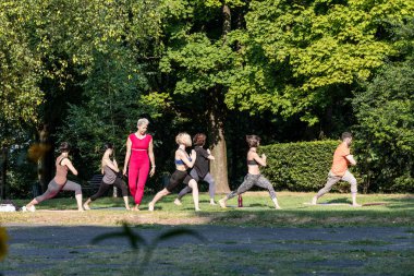 Kadın bir yoga ustası yoga eğitimi veriyor ve insanları gözlemliyor.