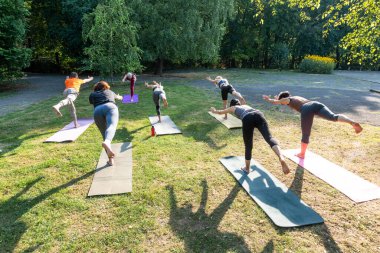 Virabgadrasan 'da spor minderindeki insanlar dengeyi geliştirmek için grup yogası yapıyorlar.