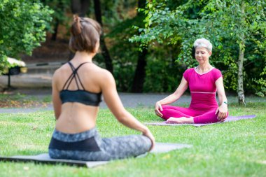 Nilüfer pozisyonunda oturan kız öğrenci yoga ustasıyla dışarıda zen yaşıyor.