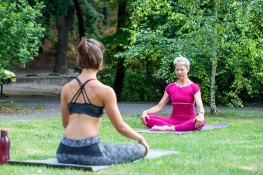 Öğrenci kız lotus pozisyonunda oturur ve yoga ustasının yanında dinlenir.