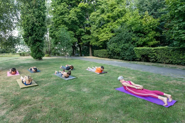 Yoga ustası eğitime başlar yüz üstü yere yatar ve ellerini arkasına koyar.