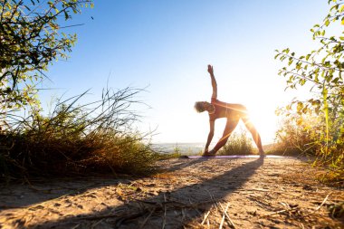 Güneş, yoga yapan bir kadının vücudunu sarar.