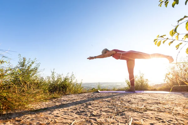 Yoga ustası gün doğumunda çimenlerde yoga yapıyor.
