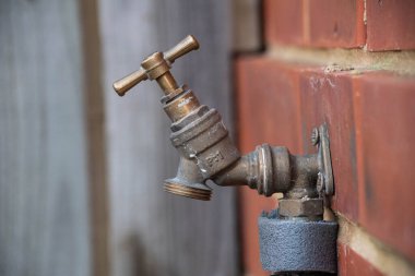 Tuğla bir evin kenarındaki ıssız musluk. Hortum takmaya hazır. 