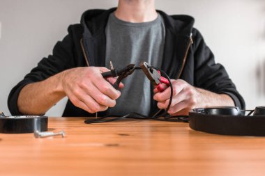 Evde pense ve tutucuyla tel kesen bir adam var. DIY tamir konsepti
