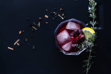 Böğürtlenli, biberiyeli ve limonlu kırmızı şarap kokteyli. Koyu düz arkaplan ile üst görünüm. 