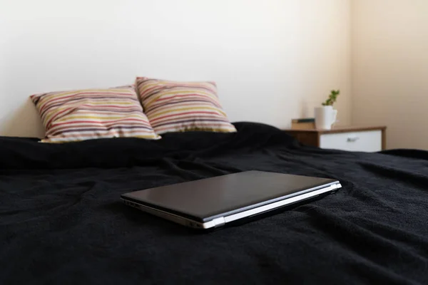 Black Laptop closed on the bed. Concept of telework and home-office.