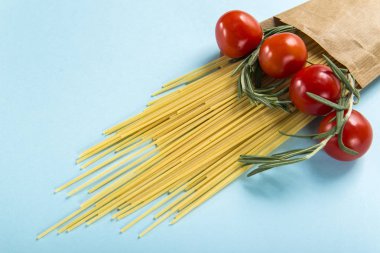 Pişmemiş İtalyan Makarna Makarna kiraz domates ve biberiye açık mavi renkli üzerinde birlikte kağıt torbaya yakın çekim