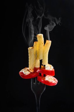 Pişmiş İtalyan Makarna, Penne rigate domates ve mayonez siyah bir çatalla üzerinde. Karanlık bir arka plan ile sıcak buhar
