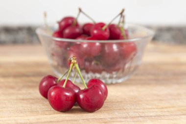 kase kırmızı kiraz ve ön plan beş kiraz, her şey üzerinde ahşap bir yüzeydir