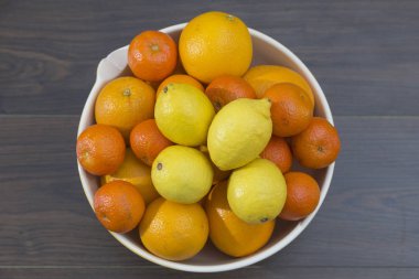 bir meyve kasesi Mediterranean narenciye, limon, portakal, mandalina ile üstten görünüm kahverengi tonlarında karanlık bir arka plan üzerinde