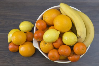 Turunçgiller ve muz, portakal, limon ve mandalina, yanında birkaç narenciye yere küçük bir grup ile bir meyve kase havai görünümü