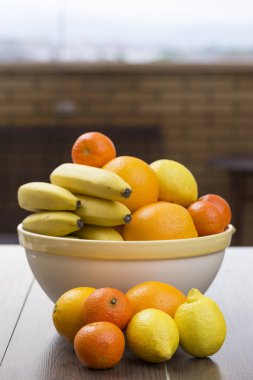meyve narenciye dolu ve sanki onlar katılmadı ön tarafta bulunan bazı muz, iki limon, iki portakal ve iki mandalina kase