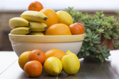 meyve narenciye dolu ve sanki onlar katılmadı ön tarafta bulunan bazı muz, iki limon, iki portakal ve iki mandalina kase