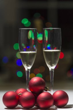 bardak şampanya renk arka plan ışıkları Noel ağacı süslemek için kırmızı topları yanındaki