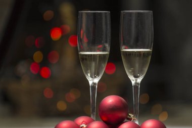 iki kadeh şampanya veya şarap renkli noktalar bir arka plan ile bazı Noel ışıkları tarafından gözlük ile bir kaç kırmızı topları dekorasyon ağaç neden.