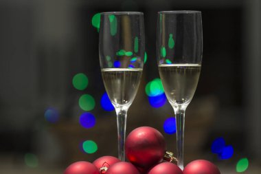 iki kadeh şampanya veya şarap renkli noktalar bir arka plan ile bazı Noel ışıkları tarafından gözlük ile bir kaç kırmızı topları dekorasyon ağaç neden.