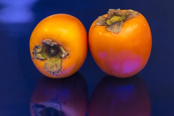 Twee Kakis Gelegen Een Ononderbroken Blauwe Achtergrond Vlezig Exotische Vruchten — Stockfoto
