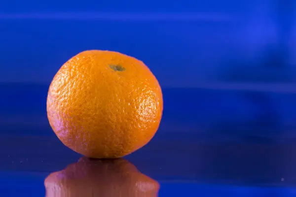 Eine Einsame Mandarine Auf Metallisch Blauem Hintergrund Mit Spiegelungen — Stockfoto