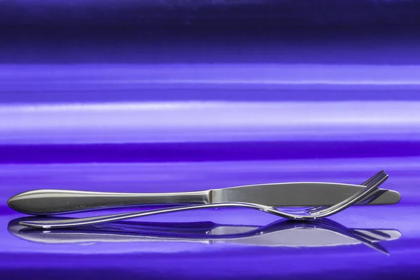 View Intertwined Fork Knife Its Reflection Endless Surface Metallic Blue — Stock Photo, Image