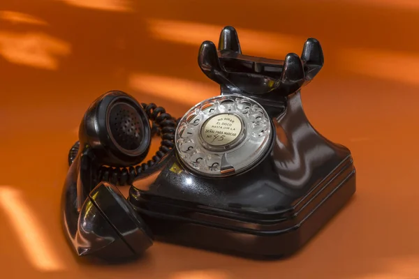 Old telephone of black color, retro telephone on orange backgrou — Stock Photo, Image