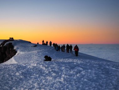 Bulutların üzerinde şafak sökerken, kili ve meru dağları Tanzanya Serengiti 'sinde. Yürüyüşçüler Afrika 'nın en yüksek dağının zirvesine doğru yol alıyorlar.