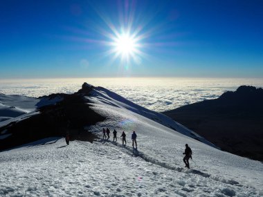 Bulutların üzerinde şafak sökerken, kili ve meru dağları Tanzanya Serengiti 'sinde. Yürüyüşçüler Afrika 'nın en yüksek dağının zirvesine doğru yol alıyorlar.