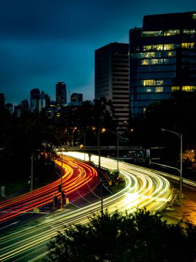 Trafiğin yoğun olduğu saatlerde Melbourne 'daki St. Kilda kavşağını hızla geçen arabaların ışık çizgileri.