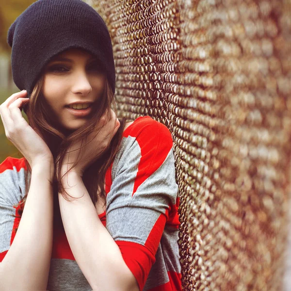 Πορτρέτο ενός όμορφου κοριτσιού με ένα hipster καπέλο και ριγέ σακάκι στην εξωτερική πύλη — Φωτογραφία Αρχείου