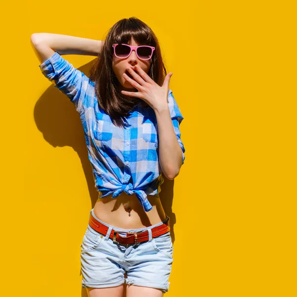 Portret pięknej zaskoczonej dziewczyny w niebieskiej koszuli i okularach na tle pomarańczowej ściany — Zdjęcie stockowe
