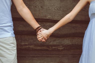 Tahta bir arka planda sevgi dolu bir çiftin elleri