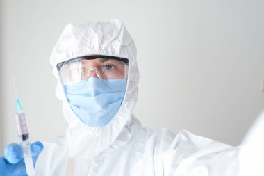 Elinde şırıngayla korunan bir doktor. Genç doktor aşıya hazırlanıyor..
