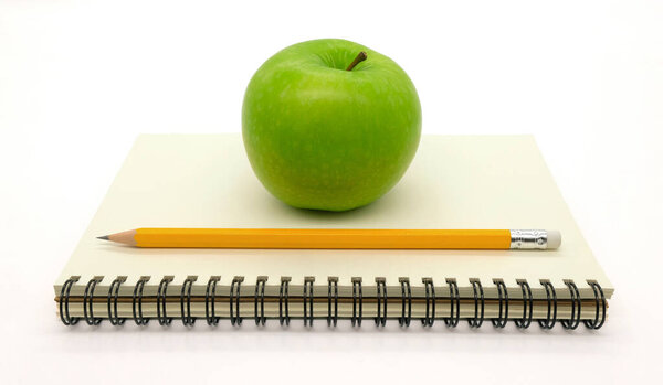 notebook with green apple on white background top view 
