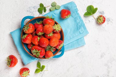 Taş arka planda bir tabakta olgun kırmızı çilekler.