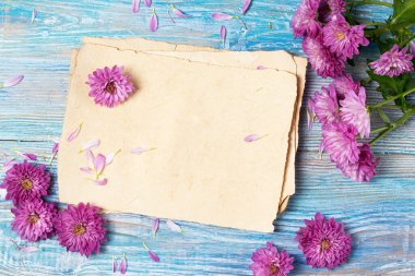 Eski boş kağıtlı ve mavi ahşap arka planda pembe çiçekli tebrik kartı.
