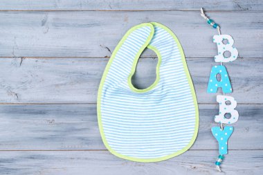 Tahta arka planda bebek önlüğü ve kelime bebeği