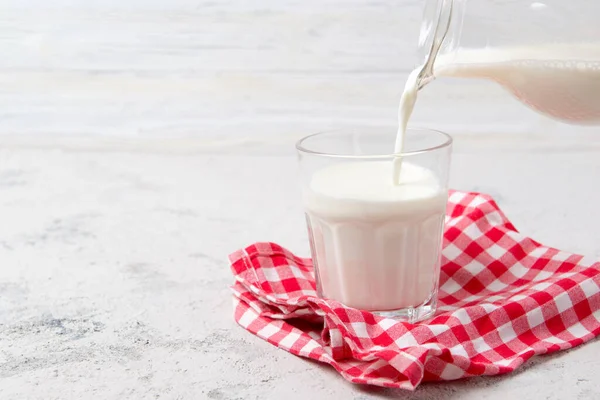 유액에서 나오는 우유를 유리잔 가벼운 배경에 바르는 — 스톡 사진